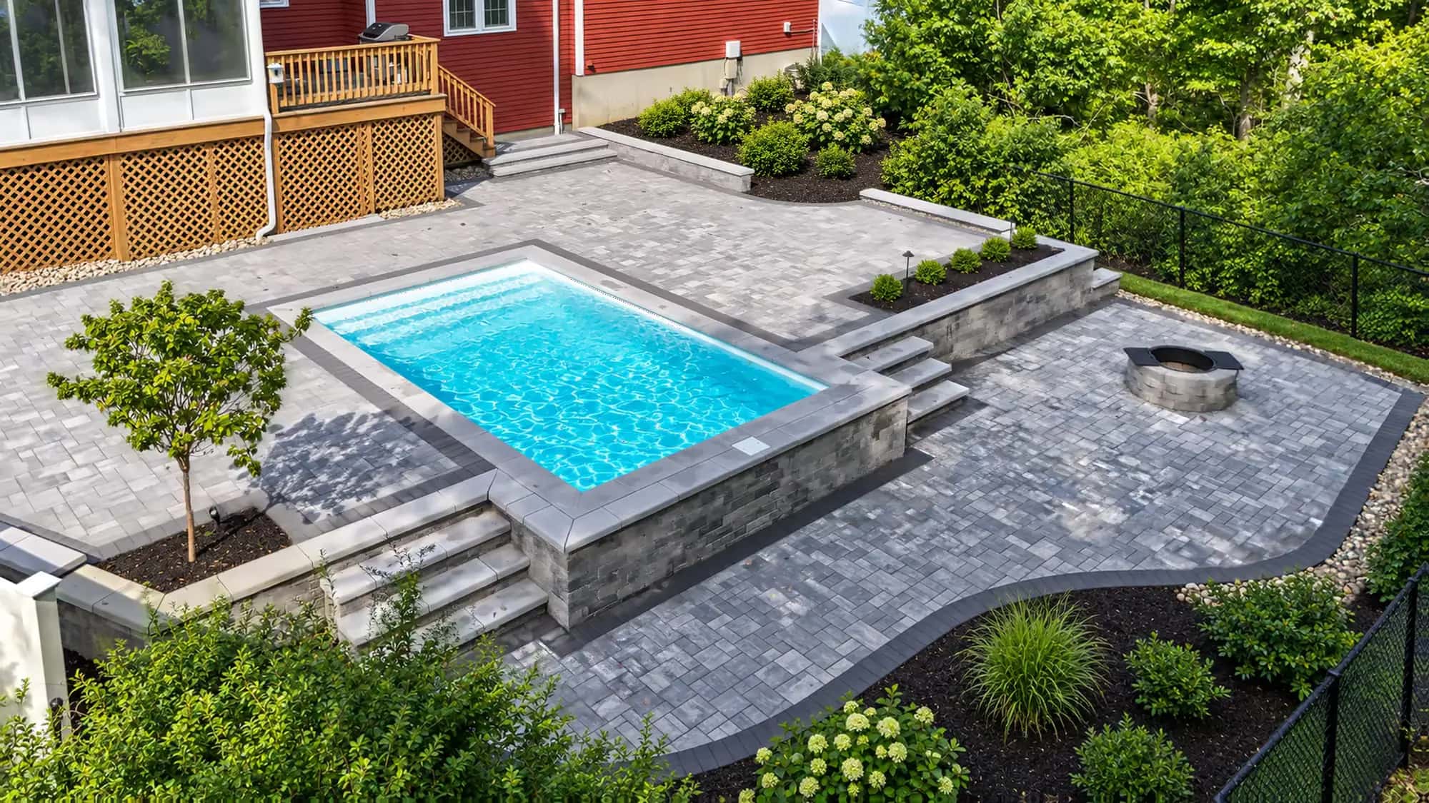 Raised Okeanos plunge pool with a block retaining wall, steps on both sides, and a lower fire-pit patio in Mansfield, MA